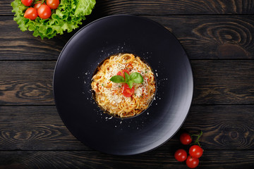 Spaghetti bolognese on black plate.