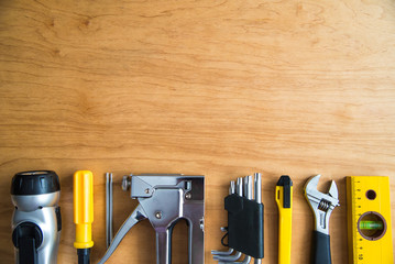 A set of tools: stapler, lantern, screwdriver, keys, cutter, level, ruler on a wooden background....
