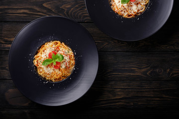 Spaghetti bolognese on black plate.