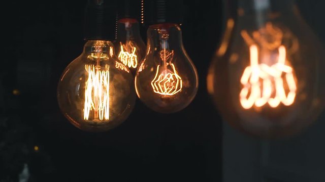 burning retro light bulbs on black background