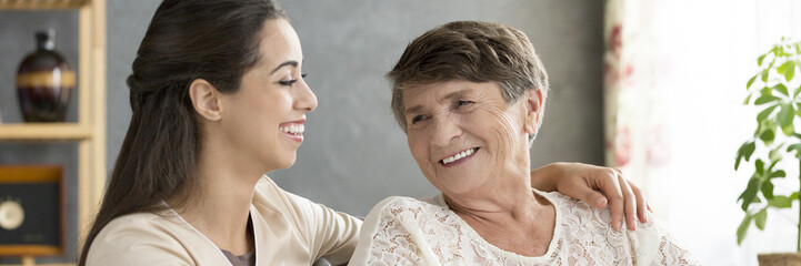 Granddaughter hugging smiling senior woman