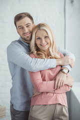 portrait of grown son hugging happy mother at home