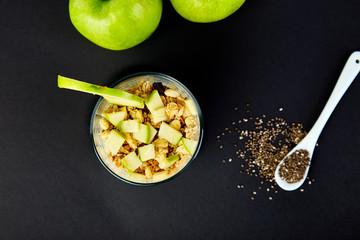 Healthy chia pudding with apples and granola in glass.