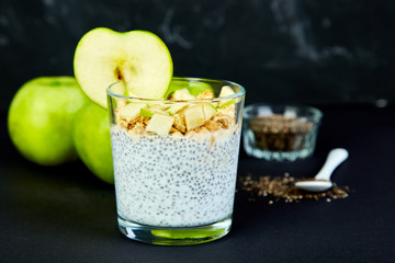 Healthy chia pudding with apples and granola in glass.