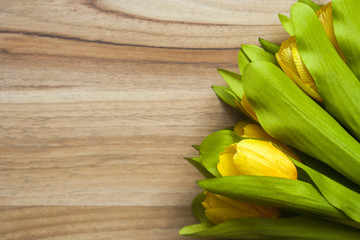 yellow tulips on wooden table background.