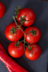 Vegetarian still life with fresh grape tomatoes, pepper and salt in wooden spoon on wooden background, selective focus
