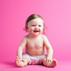 Cute toddler in a diaper on pink background