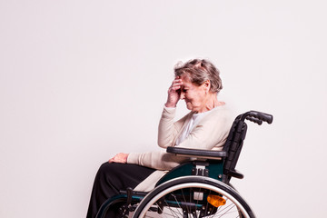 Fototapeta na wymiar Portrait of a senior woman with wheelchair in studio.