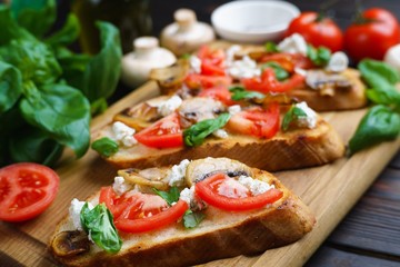 Delicious Italian bruschetta with chopped tomatoes, champignons, ricotta and basil, close up. Tasty Italian summer snack