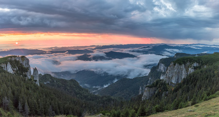 Panorama of a beautiful mountain view with fog over the peaks at sunrise, Ceahlau massif, Eastern Carpathians, Moldova, Romania