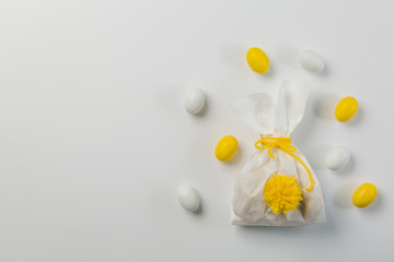Easter concept - bunny shaped bag with eggs and flowers on bright yellow background,