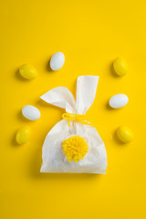Easter concept - bunny shaped bag with eggs and flowers on bright yellow background,
