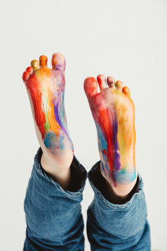 Kid's feet painted in rainbow colors.