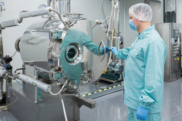 Pharmaceutical factory man worker in protective clothing working on equipment in sterile working conditions
