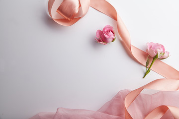 Overhead view of fresh pink shrub roses with peach colored ribbon with text space