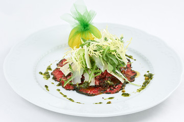 Delicious meal. Tasty carpaccio of meat with few kinds of cheese, green leaves of arugula and lemon. 