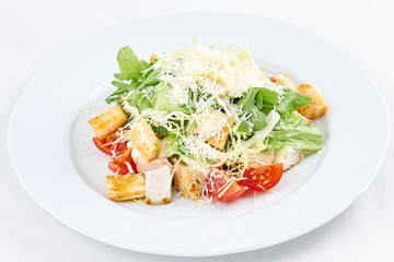 Delicious caesar salad. Caesar salad with cheese, chicken, tomatoes, rusks and green leaves of arugula.