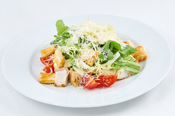 Delicious fresh caesar salad. Caesar salad with cheese, chicken, tomatoes, rusks and green leaves of arugula.