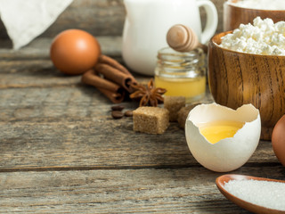 Cooking background with ingredients for making dough, cottage cheese, flour for baking, sugar and eggs on wooden rustic table Copy space
