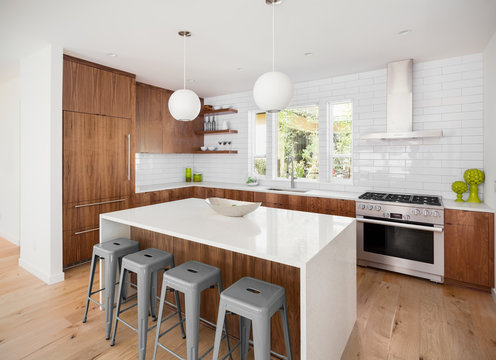 Modern Kitchen Interior in New Luxury Home with White Subway Tile, Oven and Range, Island, and Hardwood Cabinets and Floors