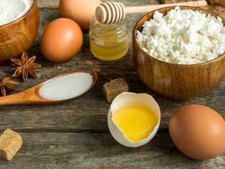 Cooking background with ingredients for making dough, cottage cheese, flour for baking, sugar and eggs on wooden rustic table Copy space