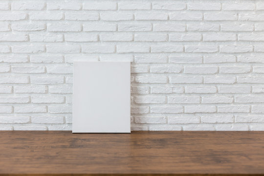 Empty white canvas frame on a wooden table