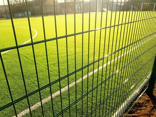 lawn field for playing minifootball behind the green fence mesh