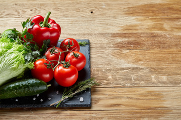 Organic closeup still life of assorted fresh vegetables and herbs on rustic wooden background, topview, selective focus.