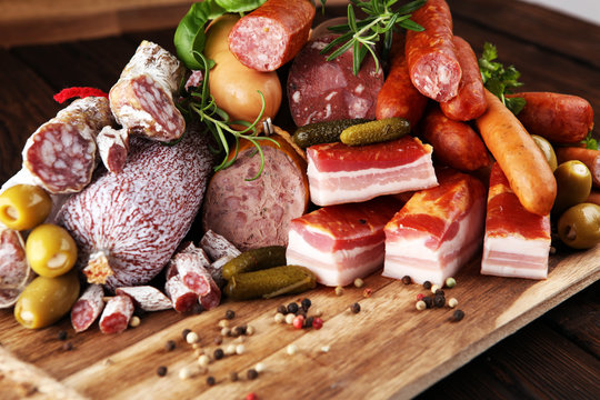 Food tray with delicious salami, ham,  fresh sausages, cucumber and herbs. Meat platter with selection