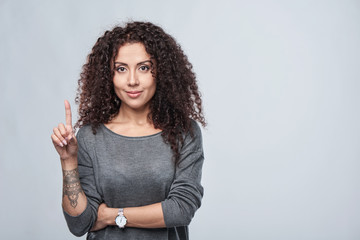 Hand counting - one finger. Curly woman pointing up at blank copy space