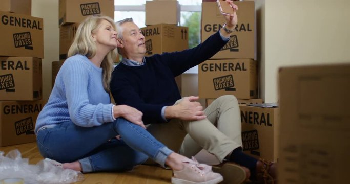 4K Happy couple on moving day taking a break from unpacking to pose for selfie