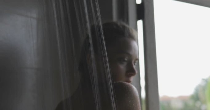 handsome young sexy woman or girl standing in the bathroom in fromt of opened window, taking shower, looking outside