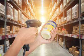 Worker checking and scanning package by laser barcode scanner in modern warehouse.