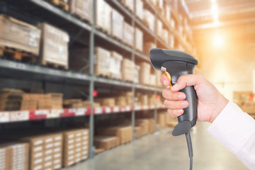 Worker checking and scanning package by laser barcode scanner in modern warehouse.