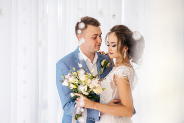 The groom hugs the bride in the room.