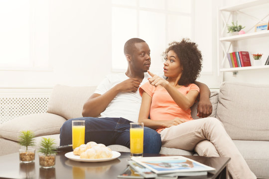 Scared african-american couple watching TV at home