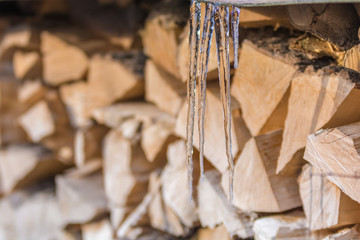Eiszapfen vor gespaltenem Brennholz im Winter