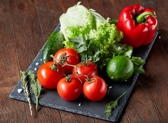 Close-up still life of assorted fresh vegetables and herbs on vintage wooden background, top view, selective focus.