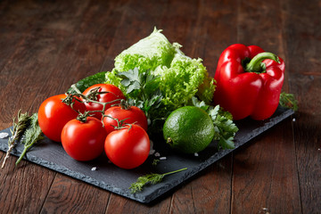 Close-up still life of assorted fresh vegetables and herbs on vintage wooden background, top view, selective focus.