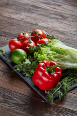 Close-up still life of assorted fresh vegetables and herbs on vintage wooden background, top view, selective focus.