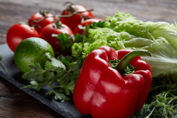 Close-up still life of assorted fresh vegetables and herbs on vintage wooden background, top view, selective focus.