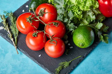 Refreshing close-up still life of assorted fresh vegetables and herbs on blue background, top view, selective focus.