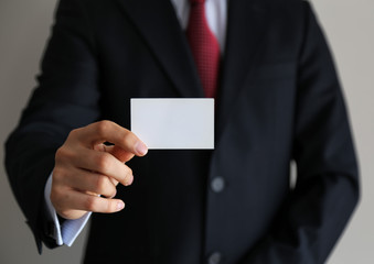 Man's hand showing business card - closeup shot on grey background