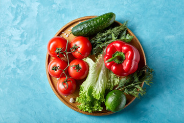 Refreshing close-up still life of assorted fresh vegetables and herbs on blue background, top view, selective focus.