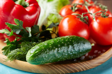 Refreshing close-up still life of assorted fresh vegetables and herbs on blue background, top view, selective focus.