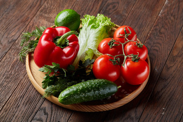 Close-up still life of assorted fresh vegetables and herbs on vintage wooden background, top view, selective focus.