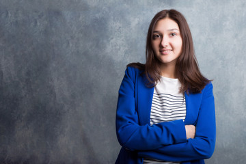 A young pretty smiling girl against a modern gray loft-style wall. She looks at the viewer. Copy...
