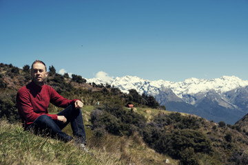 Naklejka premium Hombre joven disfrutando de las vistas de un paisaje con montañas evadas en Nueva Zelanda