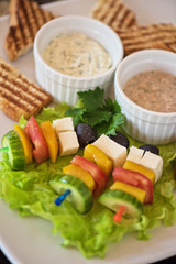 Tasty snacks: roasted toast with cheese vegetables and olive on the stick. Served with two kind of sauce