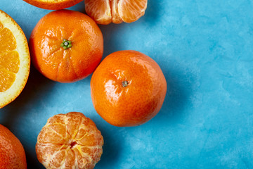 Variety of fresh citrus fruits for making juice or smoothie over blue textured background, top view, selective focus.